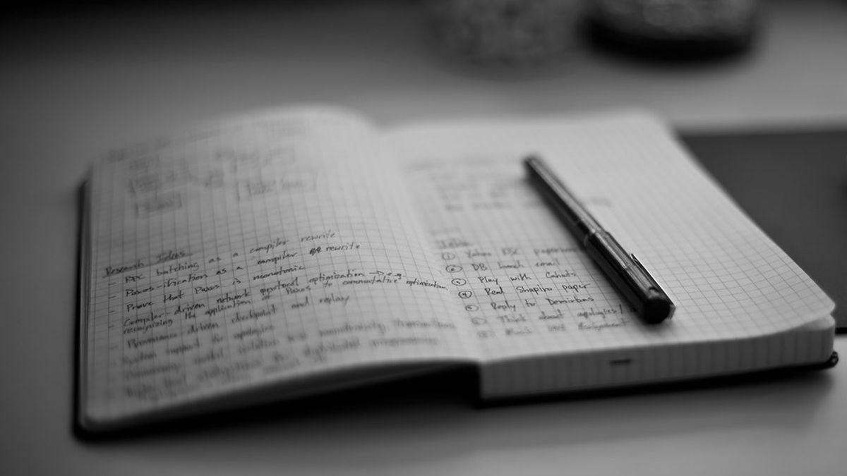 An open notebook with handwritten notes and a pen