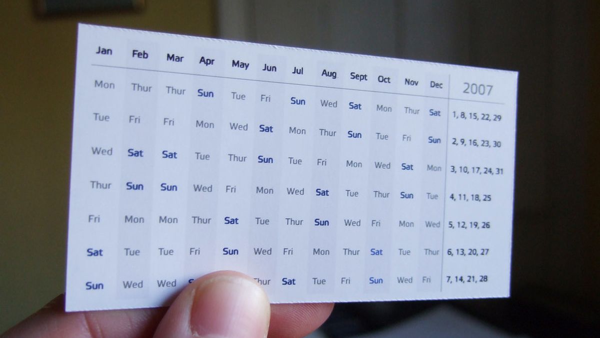 A hand holding a small yearly calendar card