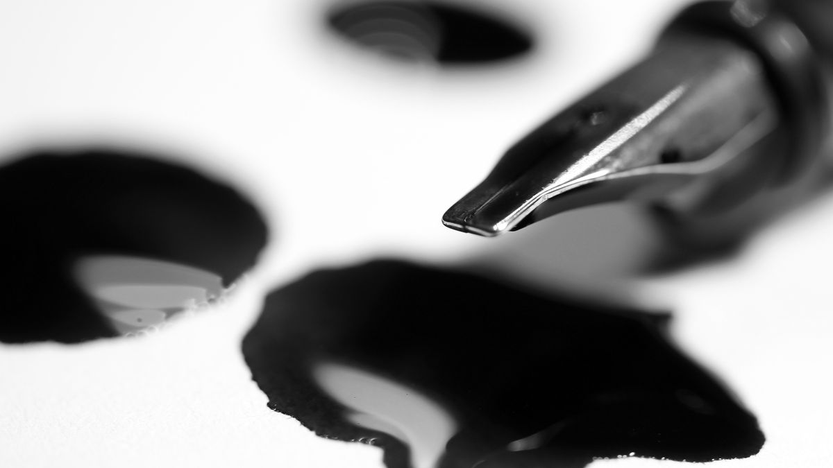 A fountain pen nib with drops of ink